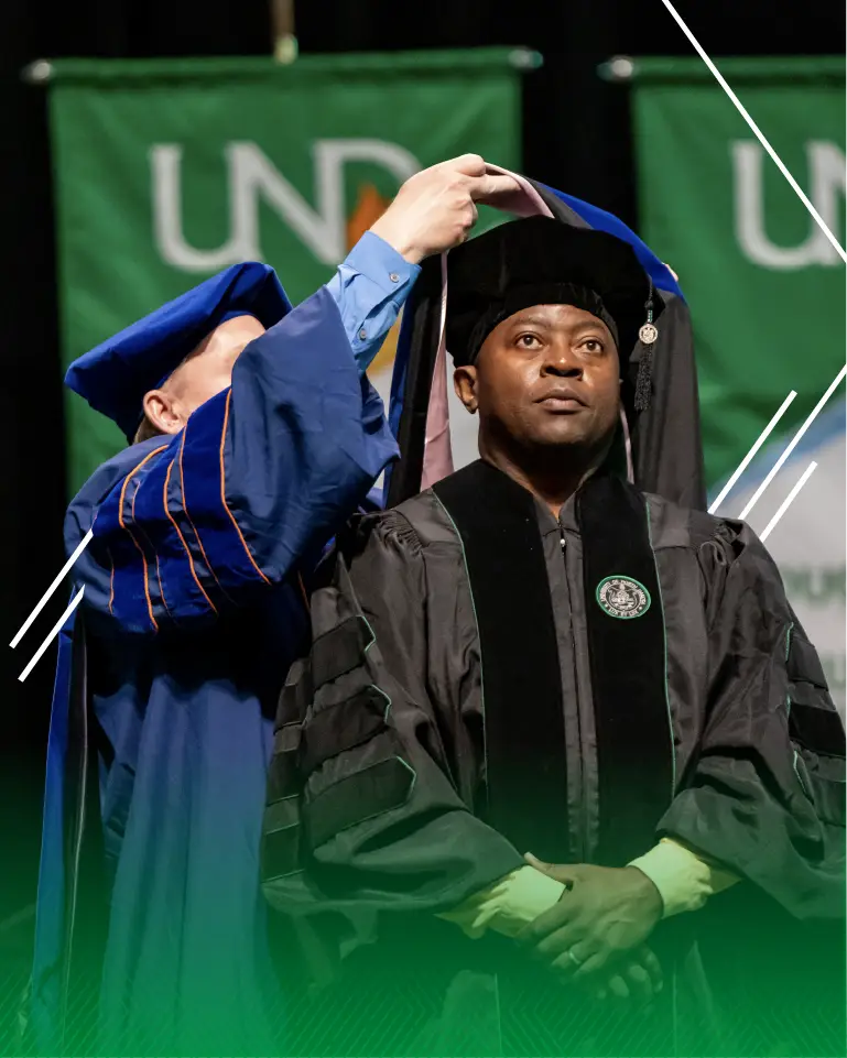 UND graduate student getting hooded at graduation ceremony