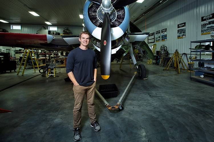 Eric Trueblood stands in front of restored war plane